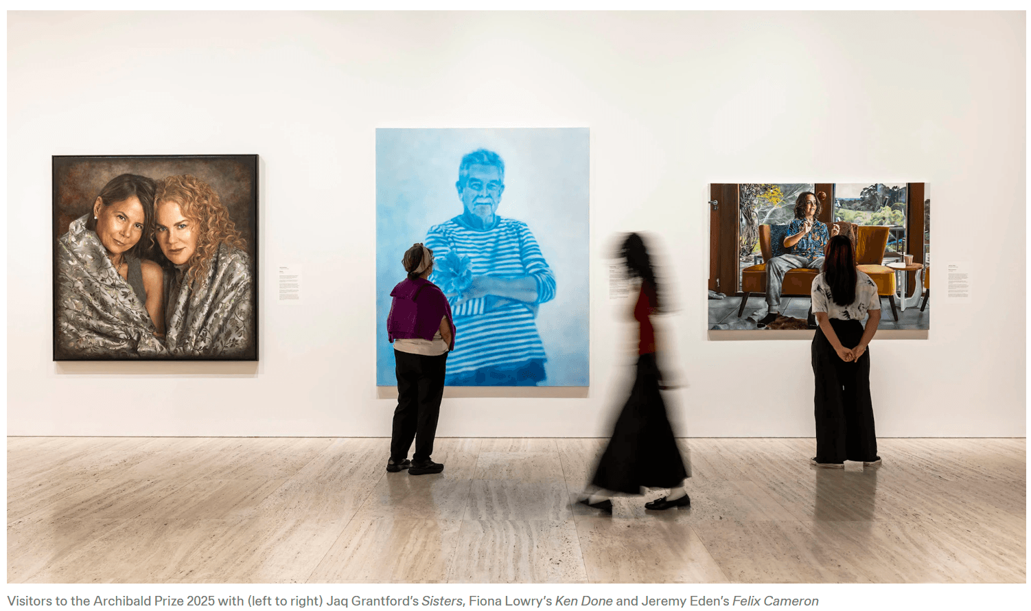 Image from the Art Gallery of NSW of three visitors to the Archibald Prize 2025 exhibition, in front of Jaq Grantford’s 'Sisters', Fiona Lowry’s 'Ken Done' and Jeremy Eden’s 'Felix Cameron'.