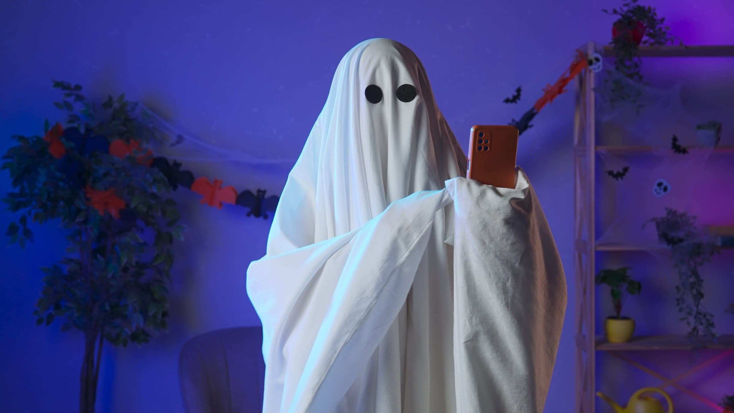 an image of a bedsheet ghost holding an iphone