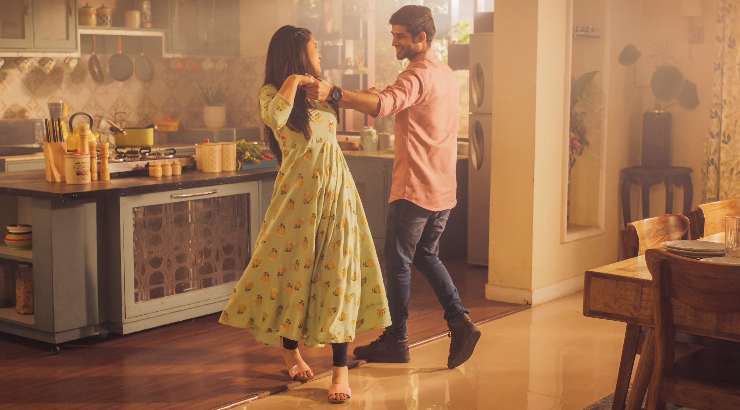 A woman and man dance together playfully in their Kitchen, enjoying each other's company.