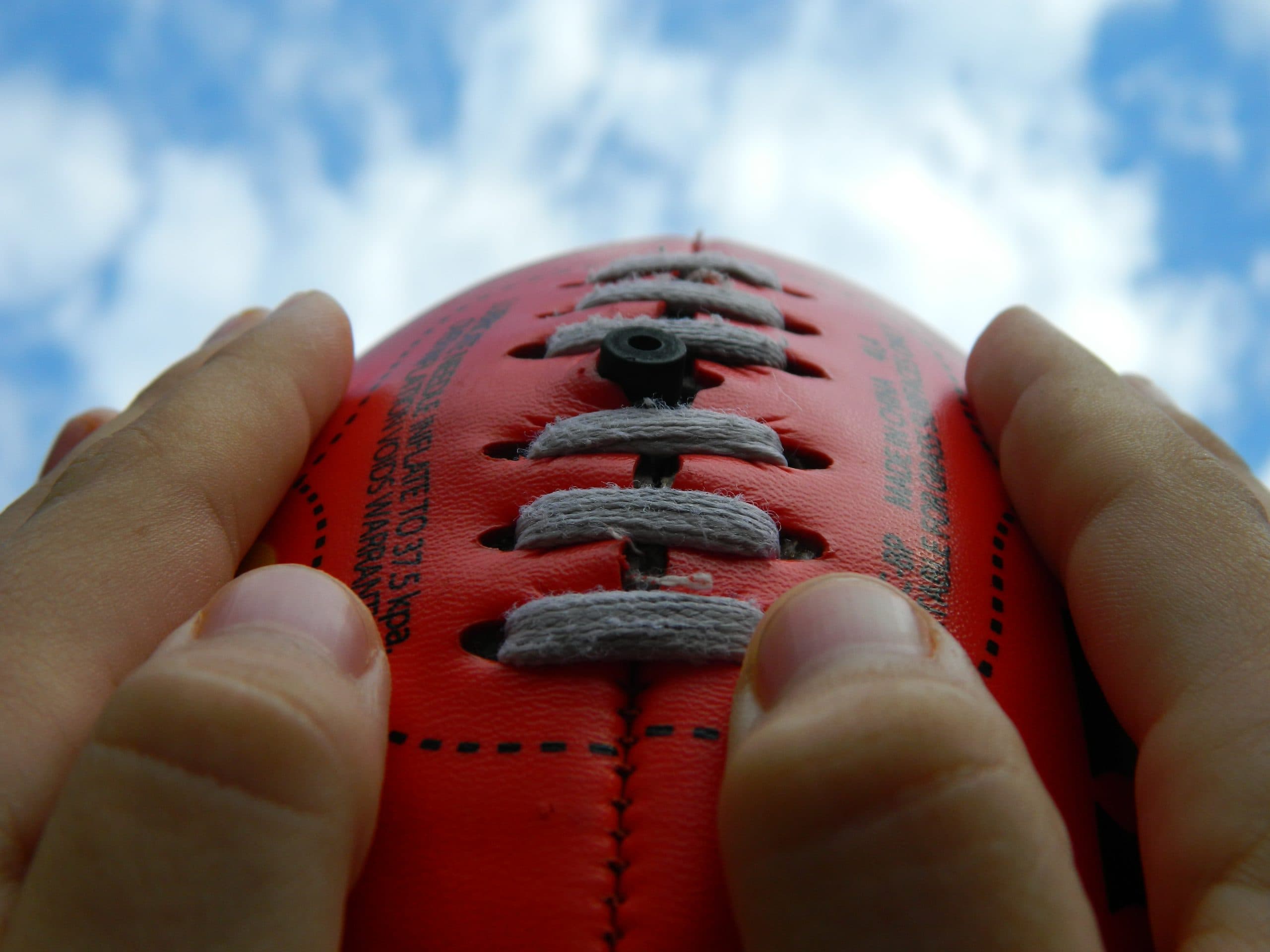 an image of a pair of hands holding an australian football league football