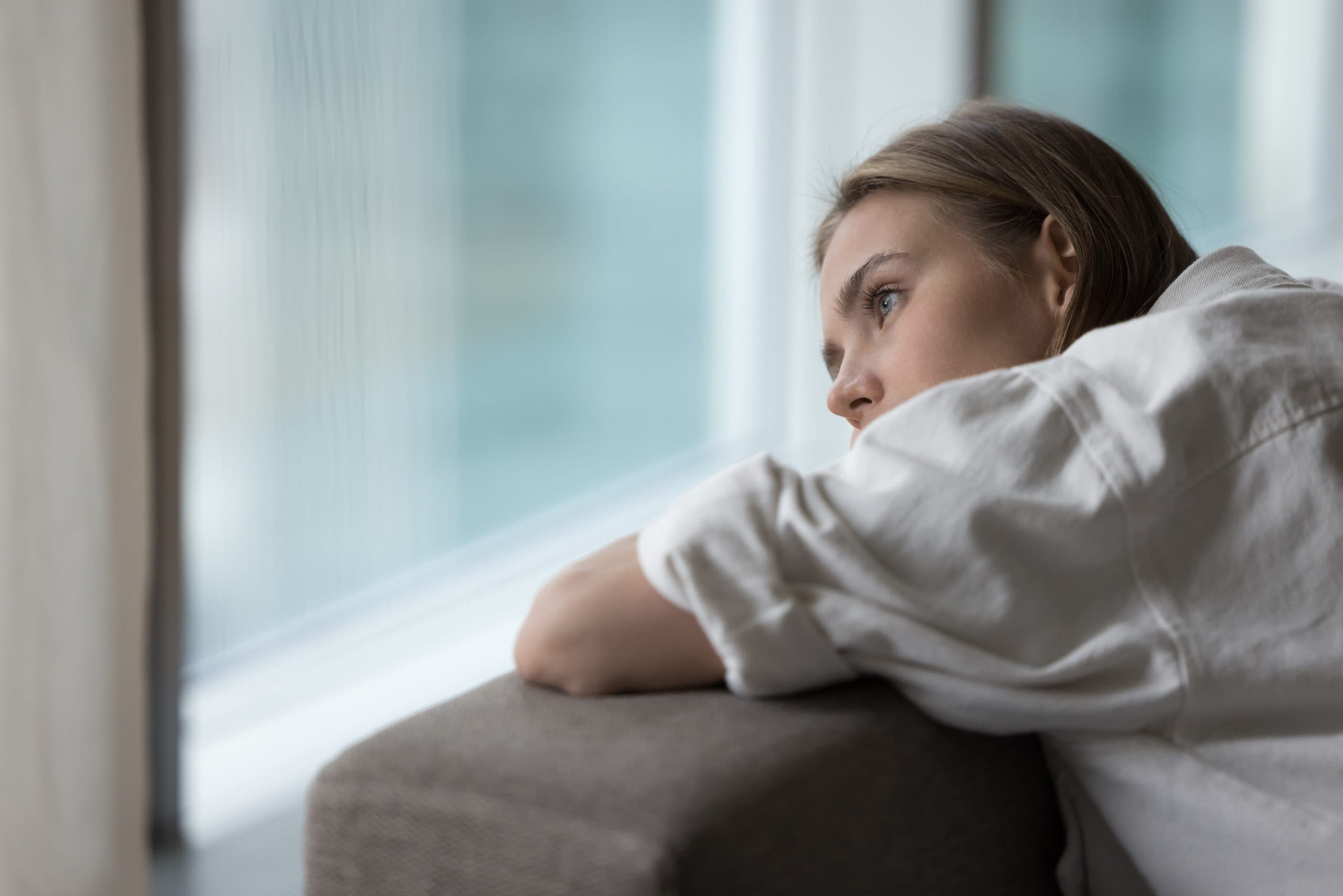 image of a young woman sitting on a couch looking out the window