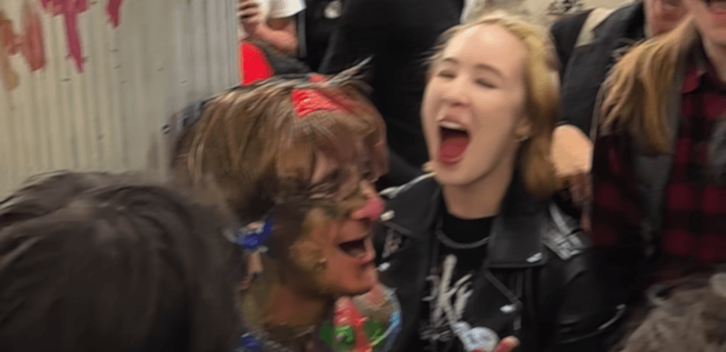 Josh Cherub taped to a pole covered in face paint