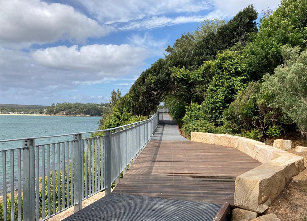 Hungry Point Cliff Top Walk in Cronulla. A view along the walkway with the boardwalk in the centre, water to the left and bushland rising up to the right.
